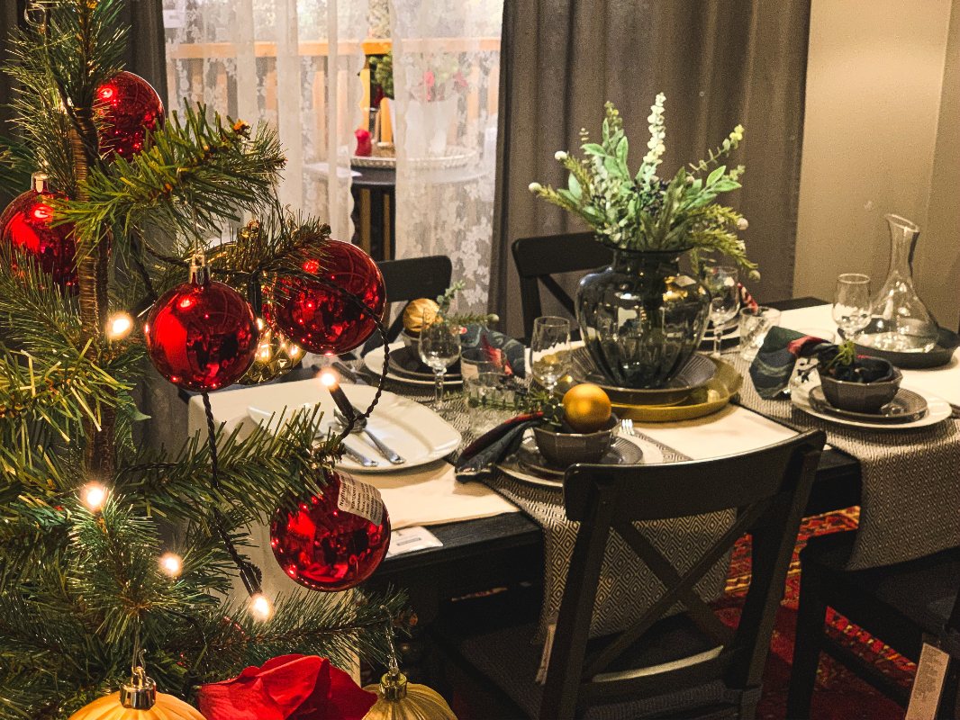 Svart bord dekket for julesesongen med fargerike julekuler og flotte planter.